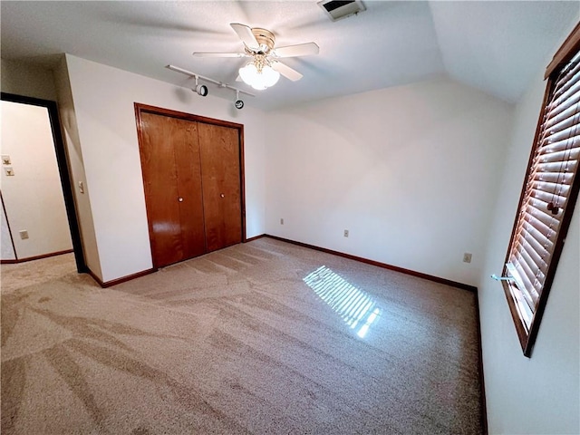 unfurnished bedroom featuring carpet flooring, visible vents, baseboards, vaulted ceiling, and a closet