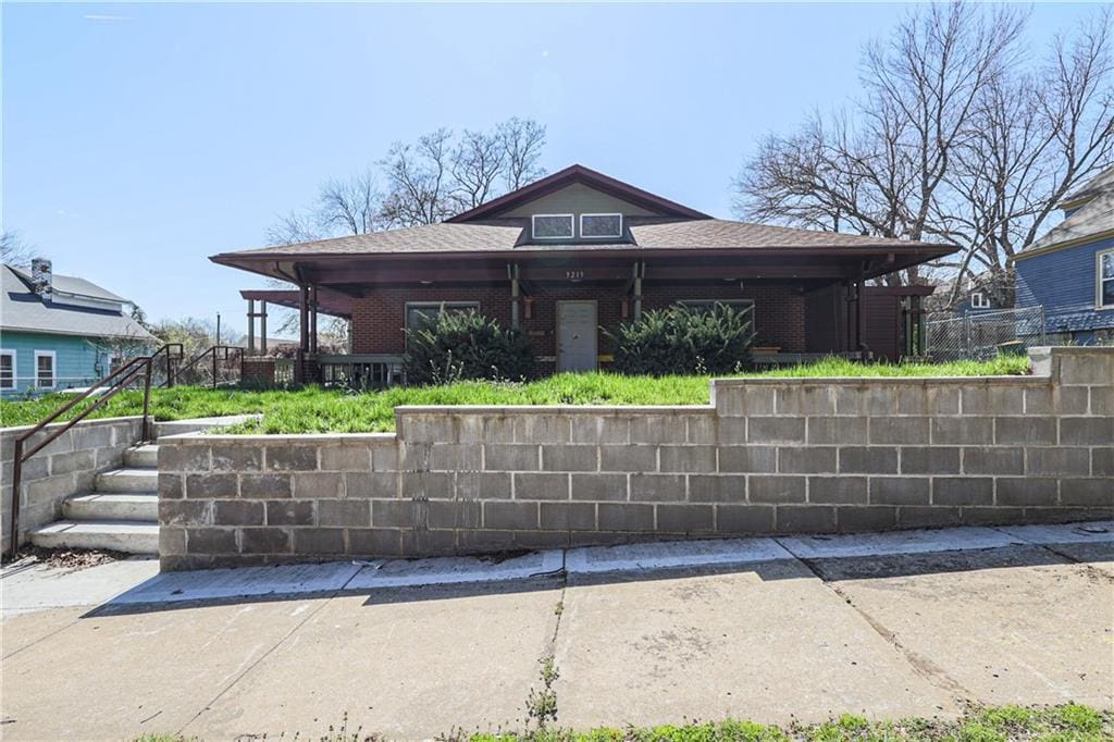view of front facade featuring brick siding and fence