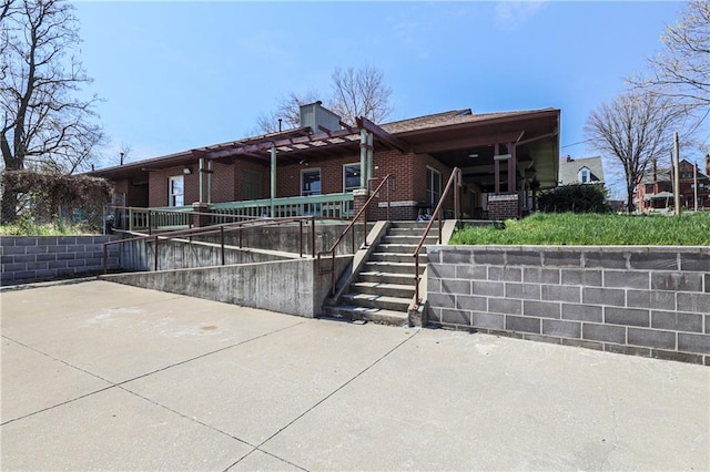 view of front facade with brick siding, a patio, and a chimney