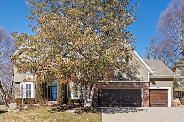 obstructed view of property featuring a shingled roof, brick siding, driveway, and stucco siding