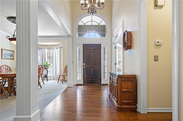 entryway with a chandelier, dark wood-style flooring, crown molding, and baseboards