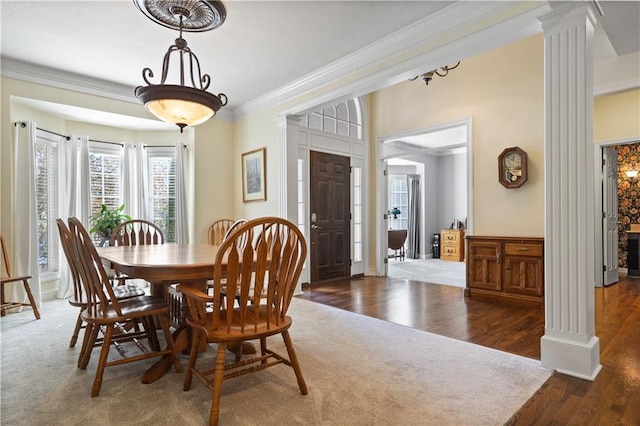 dining area featuring ornamental molding, ornate columns, and wood finished floors