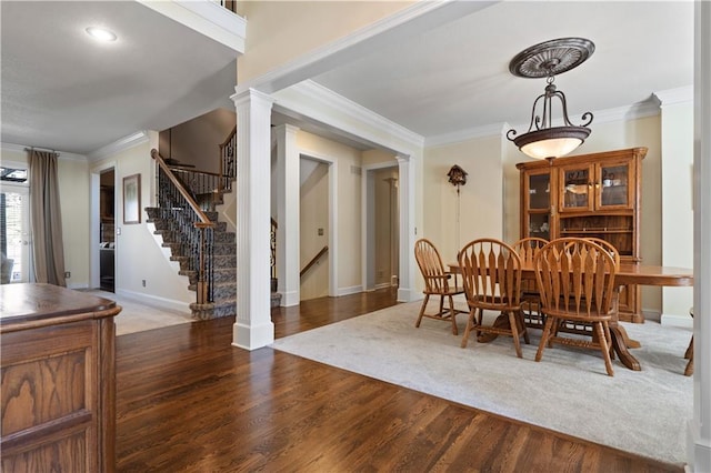 dining space with stairs, ornamental molding, wood finished floors, and ornate columns