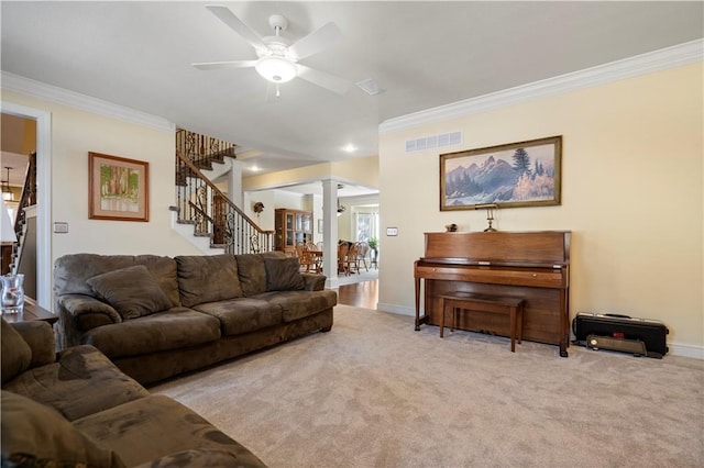 living room with carpet floors, visible vents, ornamental molding, ornate columns, and stairs