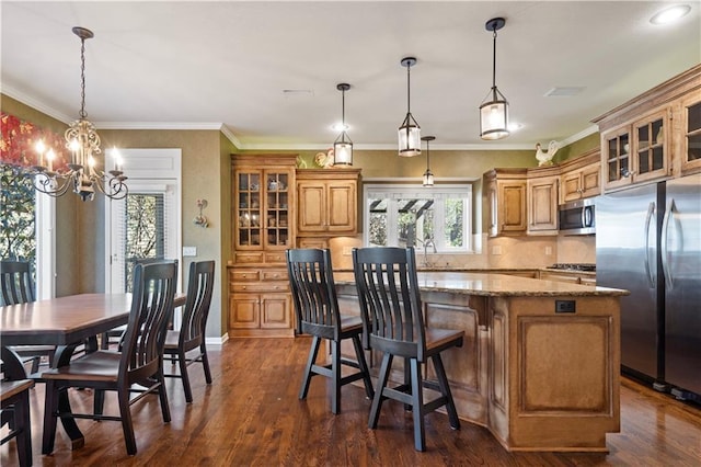 kitchen with dark wood finished floors, stainless steel appliances, tasteful backsplash, a kitchen island, and a sink