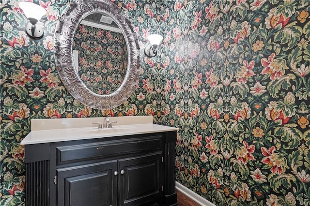 bathroom with baseboards, vanity, and wallpapered walls