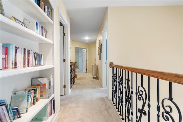 hallway with light carpet and an upstairs landing