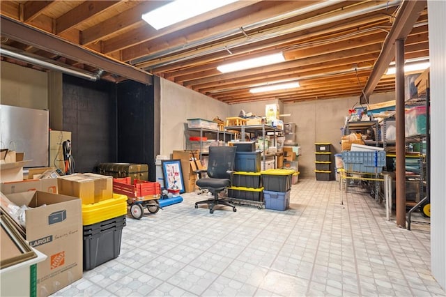 unfinished basement featuring freestanding refrigerator and tile patterned floors