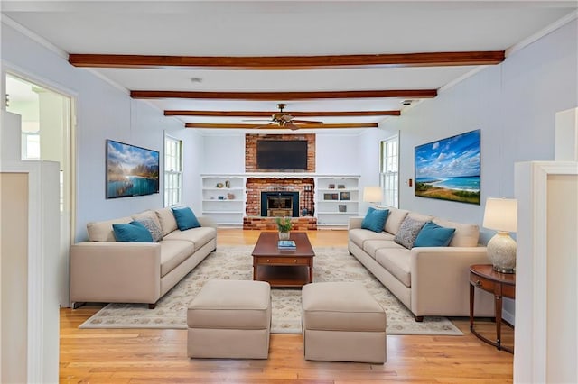 living room featuring beamed ceiling, light wood-type flooring, a fireplace, and a ceiling fan