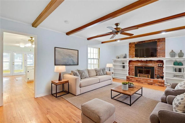 living room with crown molding, baseboards, beam ceiling, light wood-style floors, and a ceiling fan