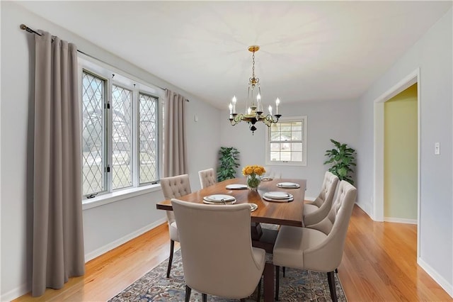 dining space with an inviting chandelier, light wood-style flooring, and baseboards