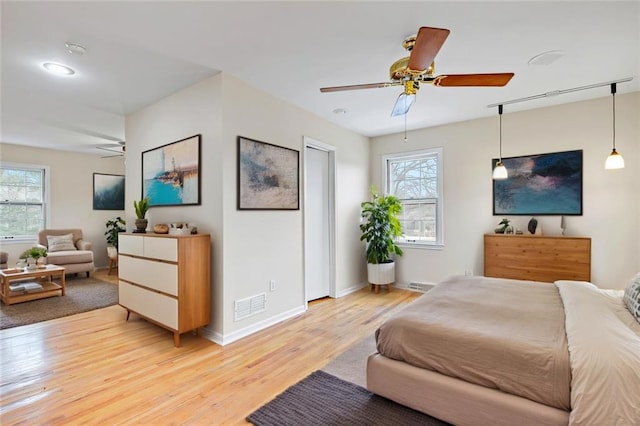 bedroom with visible vents, multiple windows, baseboards, and light wood-style floors