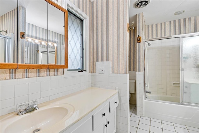 bathroom featuring wallpapered walls, tile walls, wainscoting, tile patterned flooring, and bath / shower combo with glass door