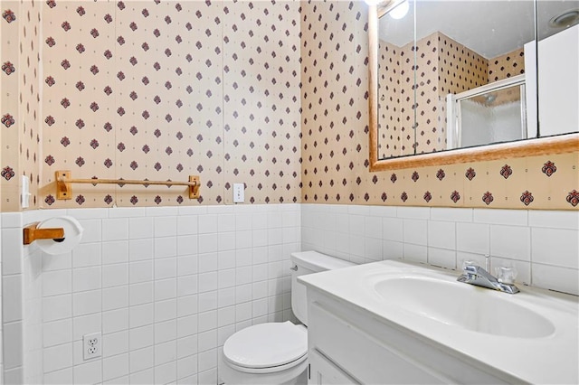 bathroom with a wainscoted wall, toilet, a stall shower, and wallpapered walls