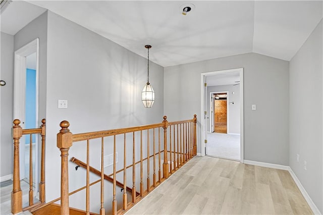 hall featuring an upstairs landing, lofted ceiling, baseboards, and wood finished floors