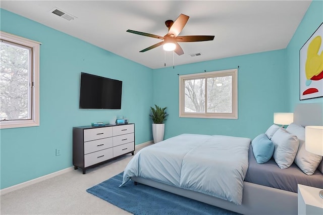 carpeted bedroom with visible vents, a ceiling fan, and baseboards