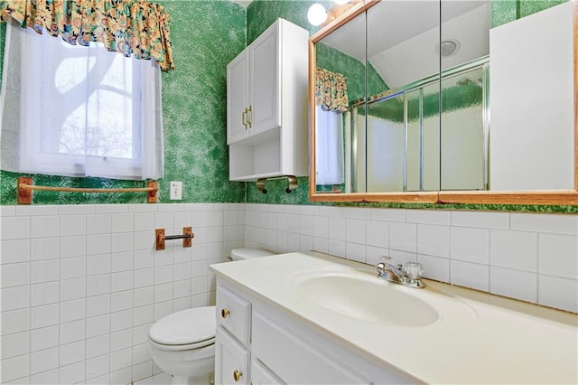 bathroom with a shower stall, wallpapered walls, toilet, wainscoting, and vanity