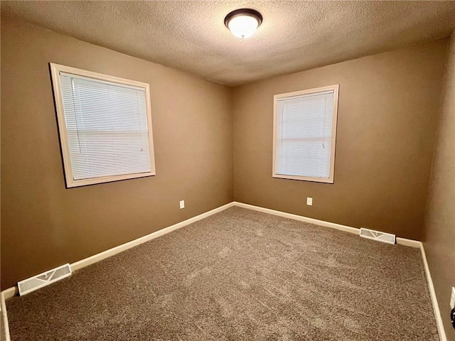 spare room with carpet flooring, visible vents, and baseboards