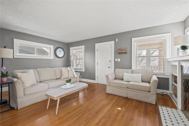 living room with baseboards, a textured ceiling, and light wood-style floors