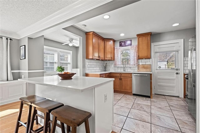 kitchen with light countertops, a kitchen breakfast bar, brown cabinetry, and stainless steel appliances