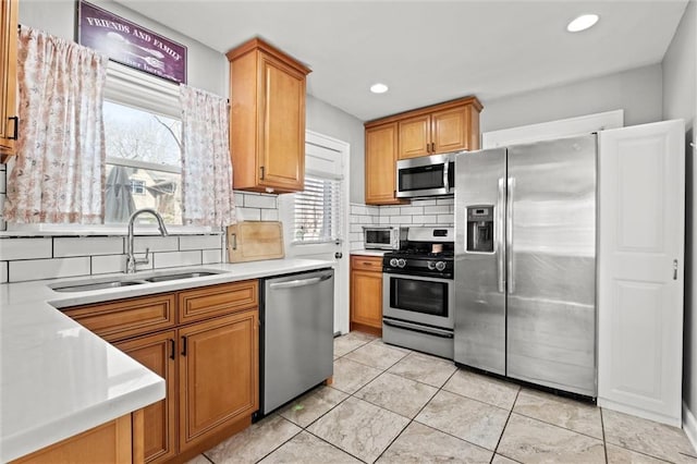 kitchen featuring a sink, recessed lighting, stainless steel appliances, light countertops, and decorative backsplash