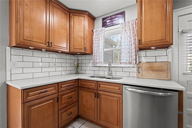 kitchen featuring tasteful backsplash, light countertops, stainless steel dishwasher, brown cabinetry, and a sink