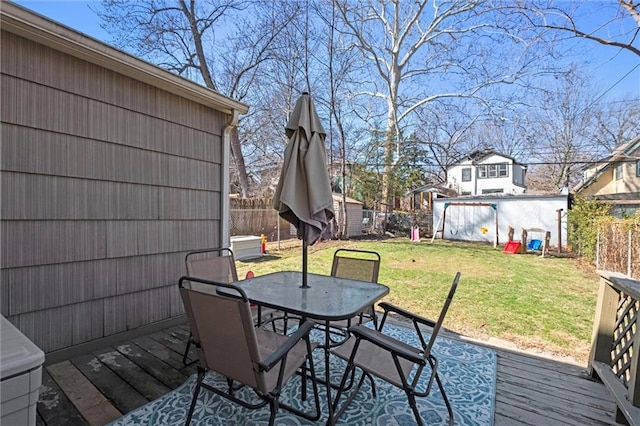 deck featuring outdoor dining space, fence, a yard, an outdoor structure, and a storage shed