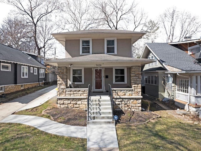 american foursquare style home with a porch, stone siding, driveway, and stucco siding