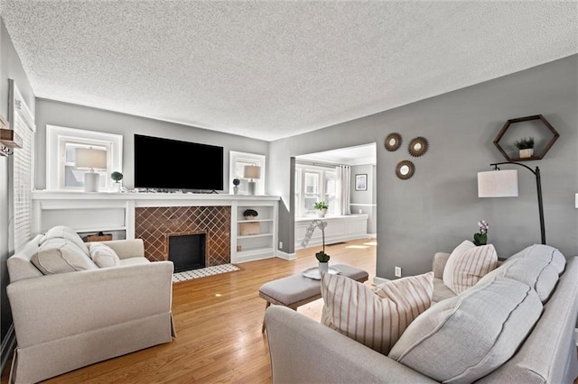 living room featuring a textured ceiling, light wood-style flooring, and a tile fireplace