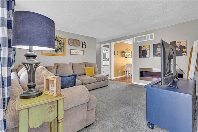 carpeted living room featuring a textured ceiling, visible vents, and baseboards