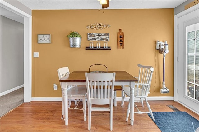 dining room featuring wood finished floors, a ceiling fan, and baseboards