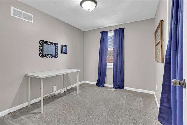 spare room featuring carpet floors, visible vents, a textured ceiling, and baseboards