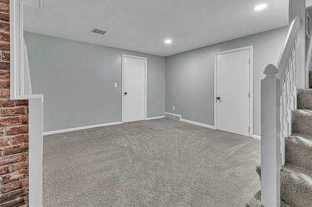 basement featuring baseboards, visible vents, stairway, and carpet flooring