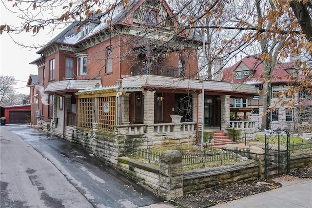 victorian house with an outbuilding, a fenced front yard, and covered porch