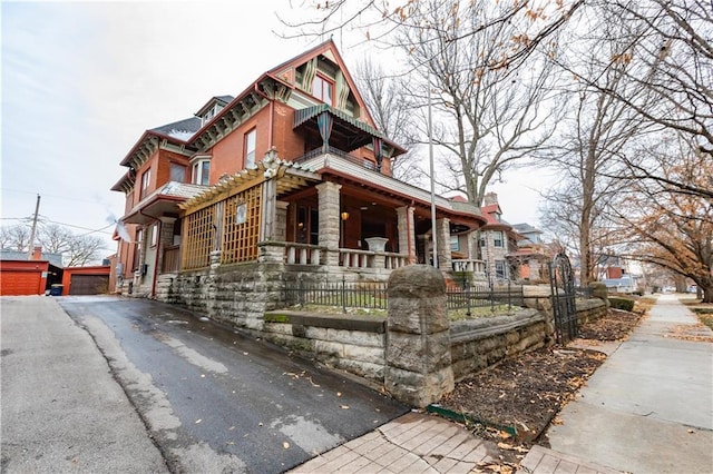 exterior space featuring covered porch, stone siding, aphalt driveway, and a fenced front yard