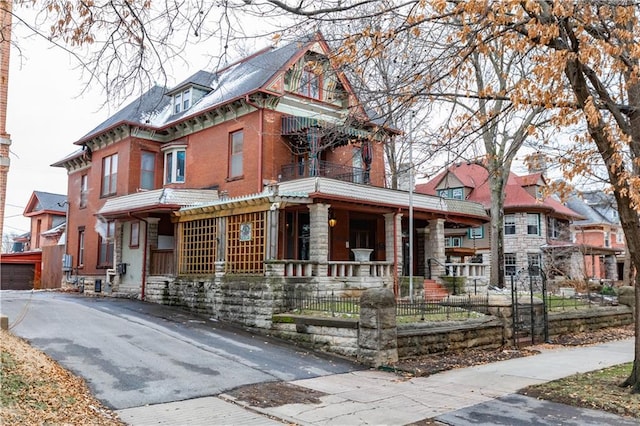 view of front of home featuring covered porch, brick siding, and fence