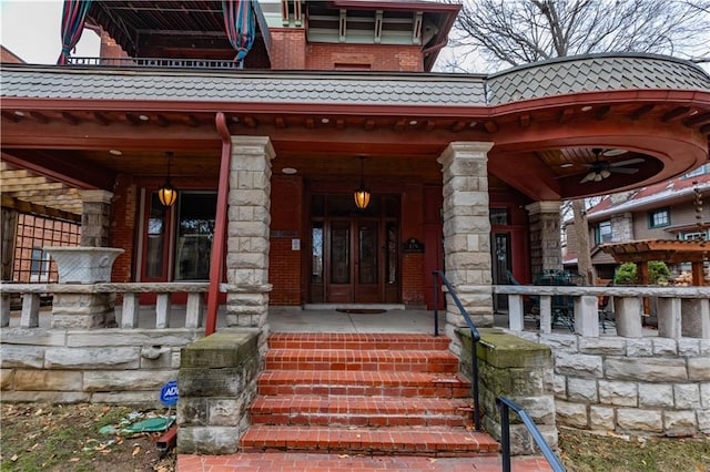 view of exterior entry with covered porch, mansard roof, and brick siding