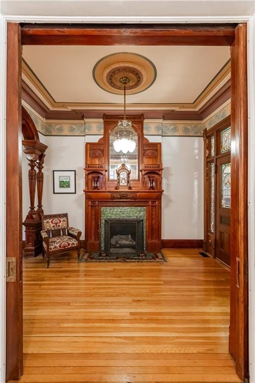 sitting room featuring light wood-style flooring, a premium fireplace, and crown molding