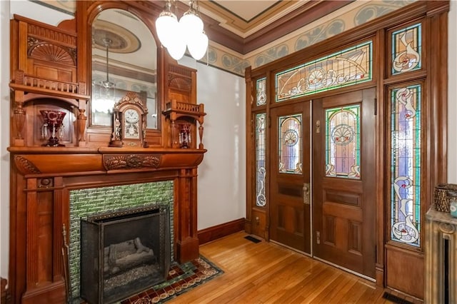 foyer featuring a fireplace, baseboards, wood finished floors, and ornamental molding