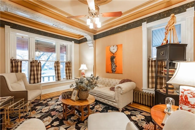 sitting room with crown molding, radiator heating unit, and wood finished floors