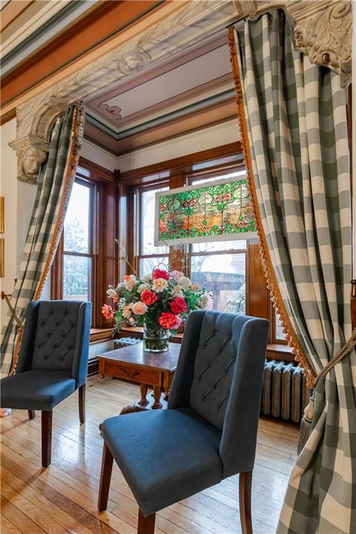 sitting room featuring light wood-style floors, radiator heating unit, and ornamental molding