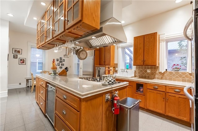 kitchen with brown cabinetry, stainless steel built in fridge, and wall chimney exhaust hood