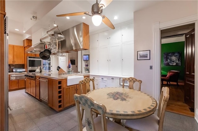 kitchen with a warming drawer, stainless steel appliances, a kitchen island with sink, and recessed lighting