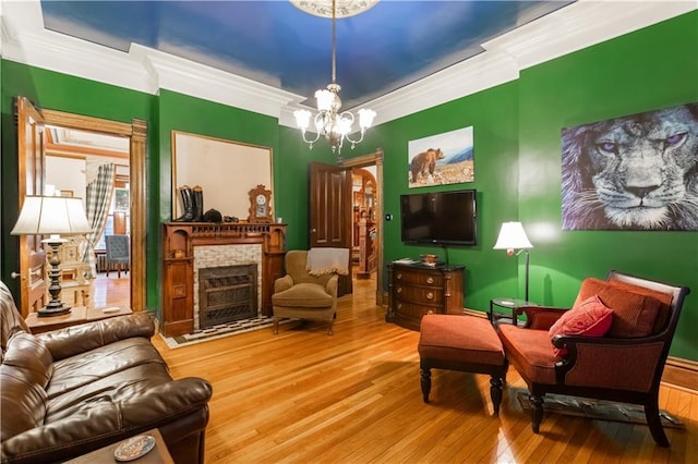 sitting room with a chandelier, a fireplace, wood-type flooring, and crown molding