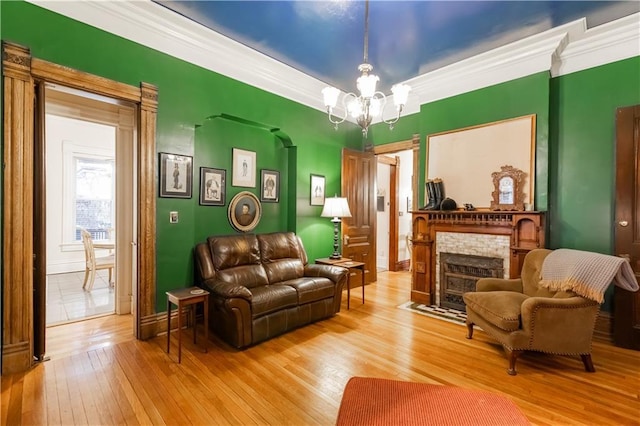 sitting room featuring hardwood / wood-style flooring, a notable chandelier, crown molding, and a fireplace with flush hearth