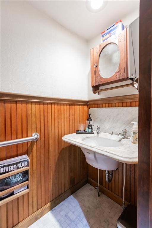 bathroom featuring a wainscoted wall, wooden walls, and tile patterned floors