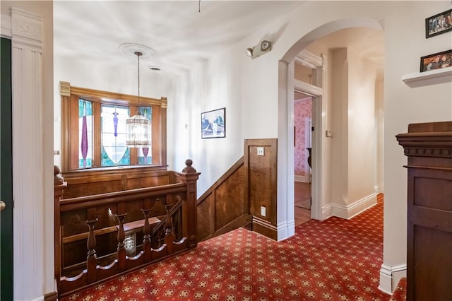 hallway with arched walkways and carpet flooring