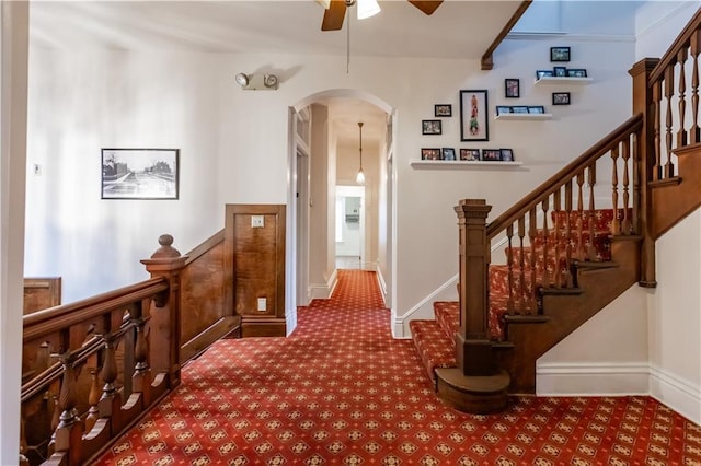 hallway with arched walkways, carpet floors, and baseboards