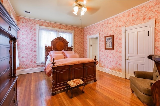 bedroom featuring wood-type flooring, visible vents, baseboards, and wallpapered walls