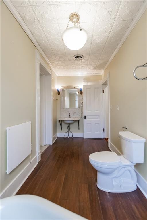 bathroom featuring baseboards, visible vents, ornamental molding, and wood finished floors